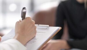 female writing on clipboard