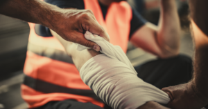 worker with injured arm being bandaged by coworker