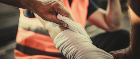 worker with injured arm being bandaged by coworker